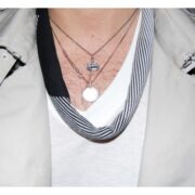 A woman wearing three different necklaces on her neck.