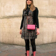 A woman in black and pink boots standing on the sidewalk.