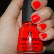 A person holding onto a red nail polish bottle