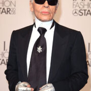 A man in black suit and sunglasses standing on the red carpet.