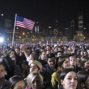 A crowd of people standing in front of an american flag.