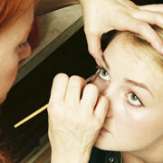 A woman is putting makeup on another person.
