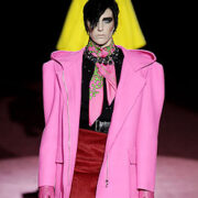 A man in pink coat and red skirt on runway.