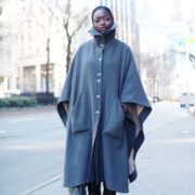 A person standing on the street wearing a coat