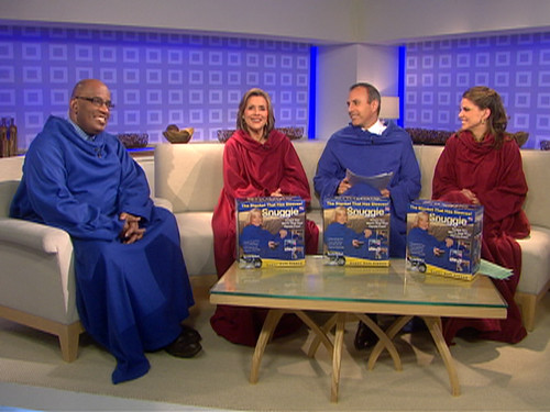 Four people sitting on a couch with blankets around them.