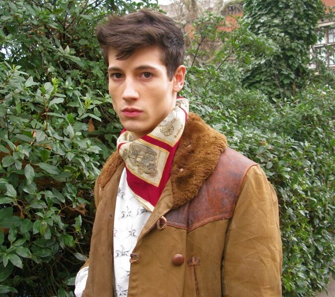 A man in a brown jacket and red scarf.