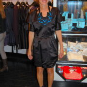 A woman in black dress standing next to a display case.