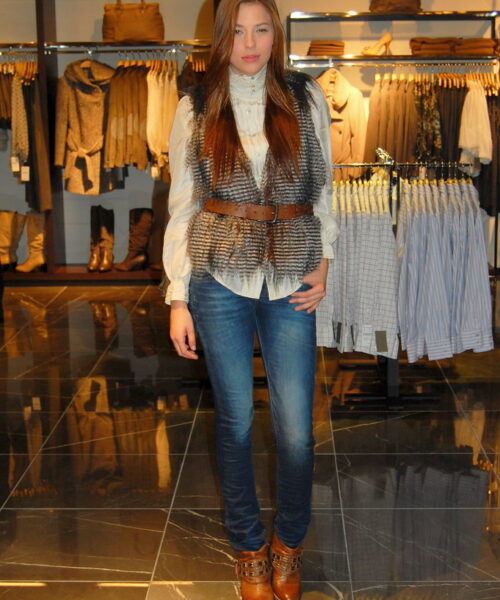 A woman in jeans and boots standing on the floor.