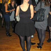 A woman in black dress and tights standing on the floor.