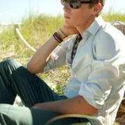 A man sitting on the ground wearing sunglasses.
