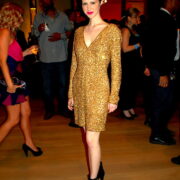 A woman in a gold dress standing on the floor.