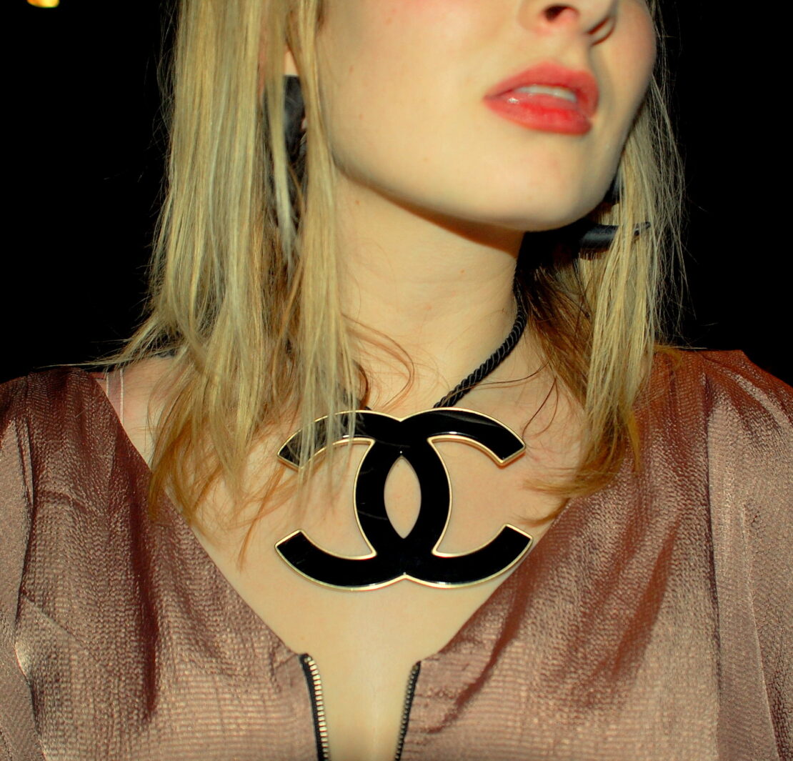 A woman wearing a necklace with the letters c on it.