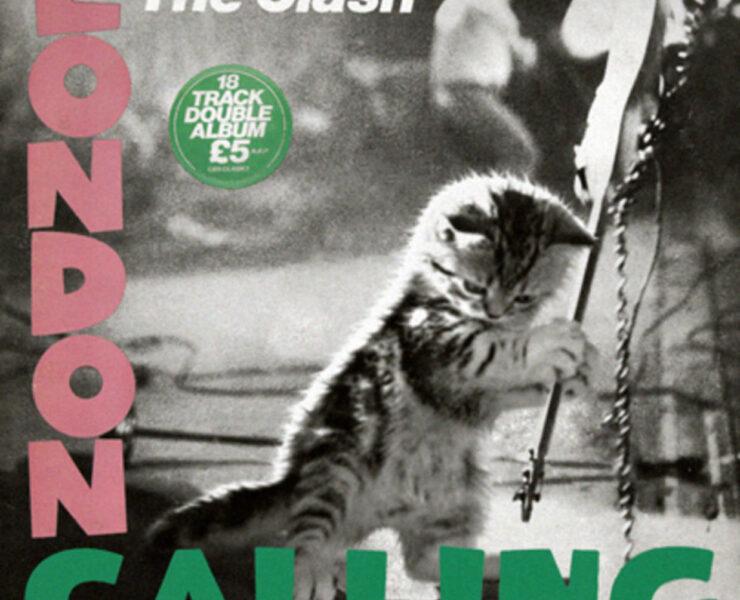 A cat is standing on the side of a pole.