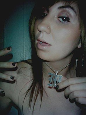 A woman with long hair and black nails holding a necklace.