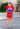 A woman in red and blue shirt dress standing on street.