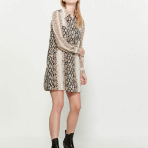 A woman in black and white dress standing next to wall.