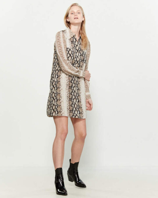 A woman in black and white dress standing next to wall.