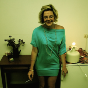 A woman in a blue dress standing next to a refrigerator.